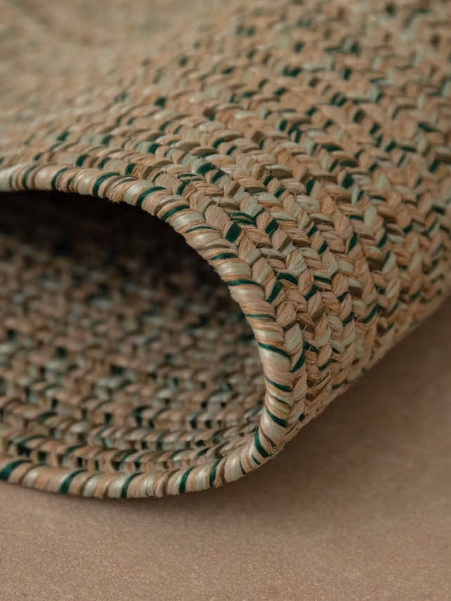 Xamena rug with a textured woven pattern featuring natural fibers and a hint of green, adding a touch of nature to your space.