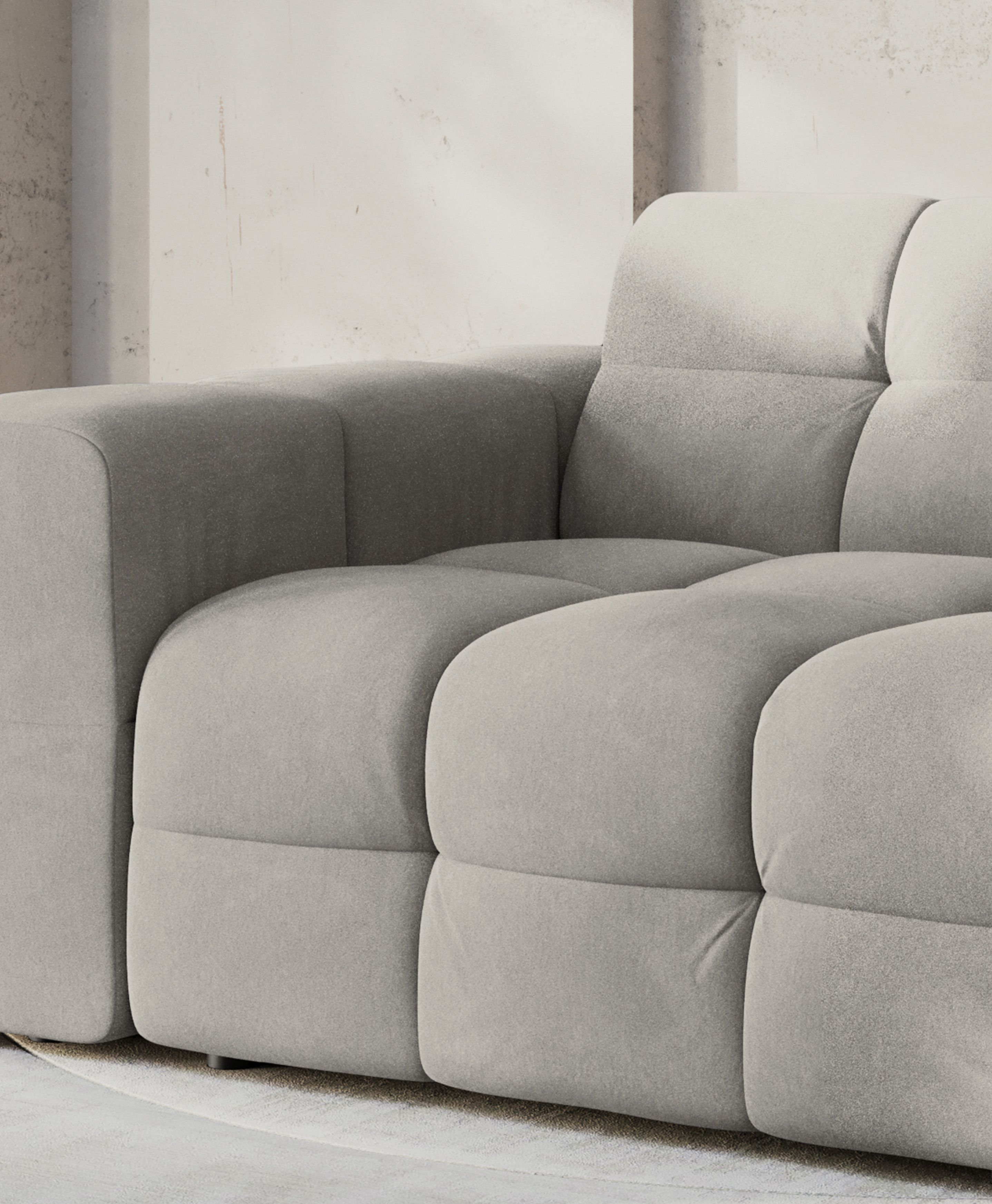Kendal sofa in soft grey fabric with tufted cushions and structured armrests, offering modern comfort and style.