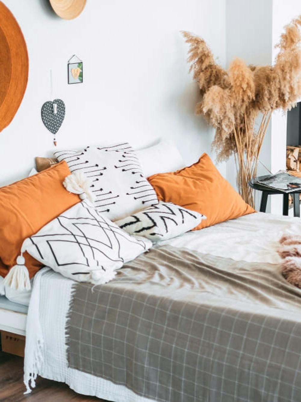 Przytulna sypialnia w stylu boho z poduszkami kocami z naturalnymi dekoracjami