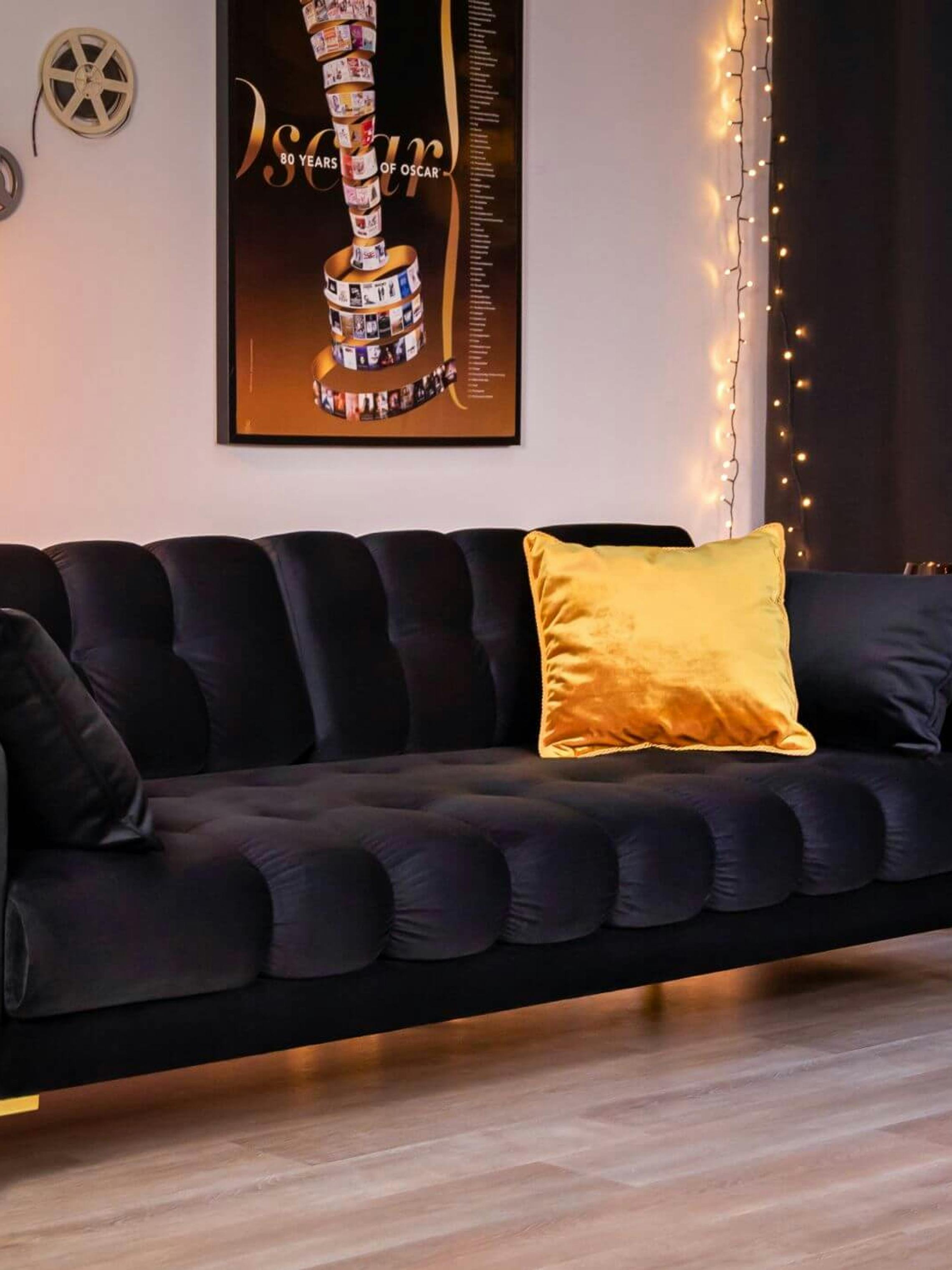 Czarna pikowana sofa jest idealnym miejscem do spędzenia wieczoru na oglądaniu filmów