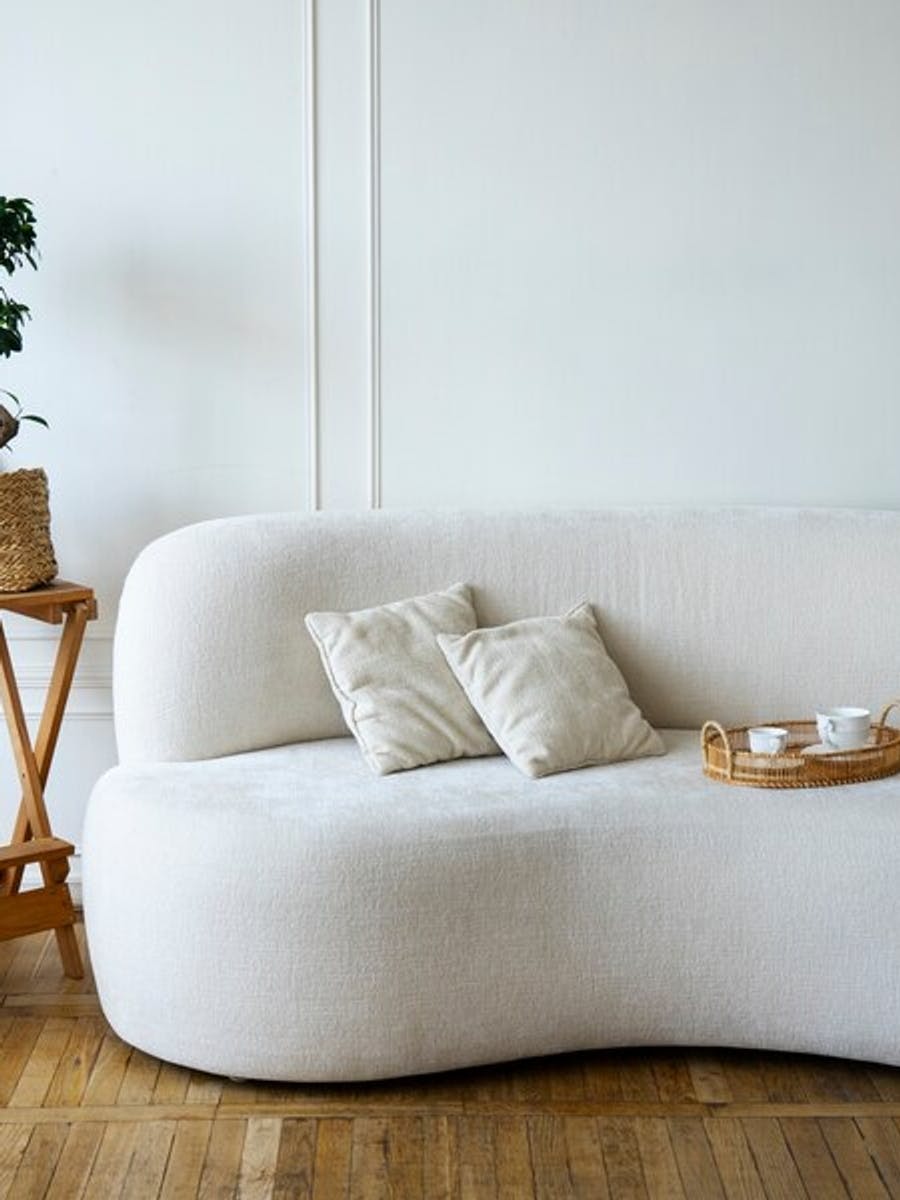 Biała sofa o zaokrąglonych kształtach pasuje do salonu w stylu japandi